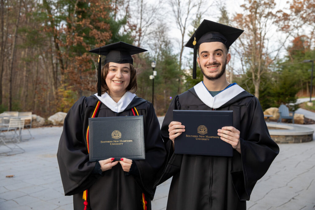 Michael and Marisa wearing their regalia and posing for photo at SNHU Commencement
