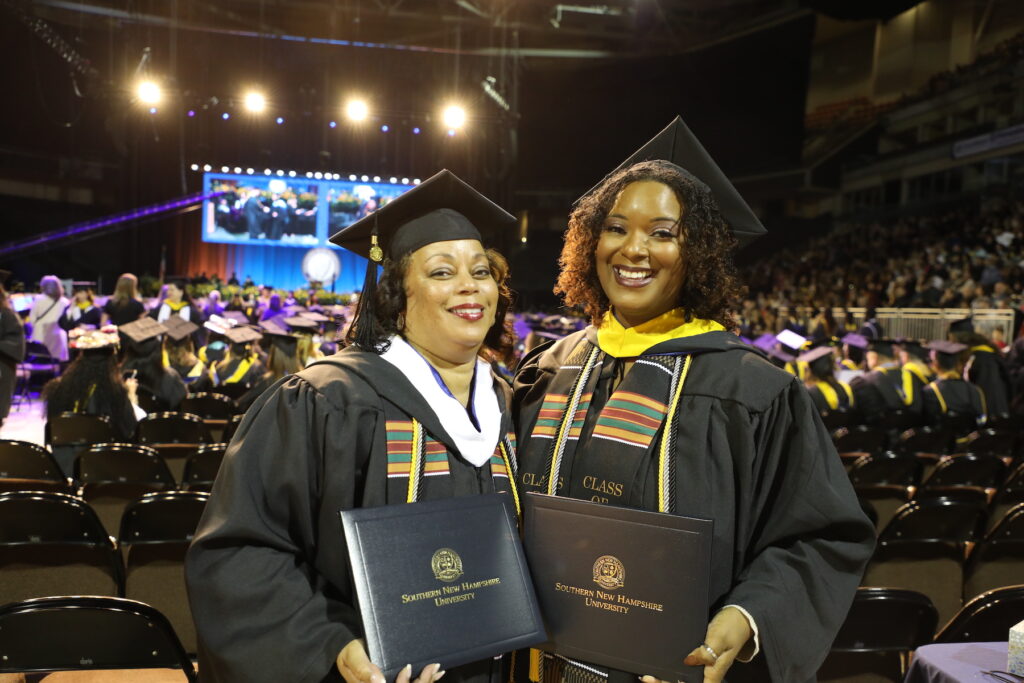Alexis and Brenda wearing their regalia and posing for photo at SNHU Commencement