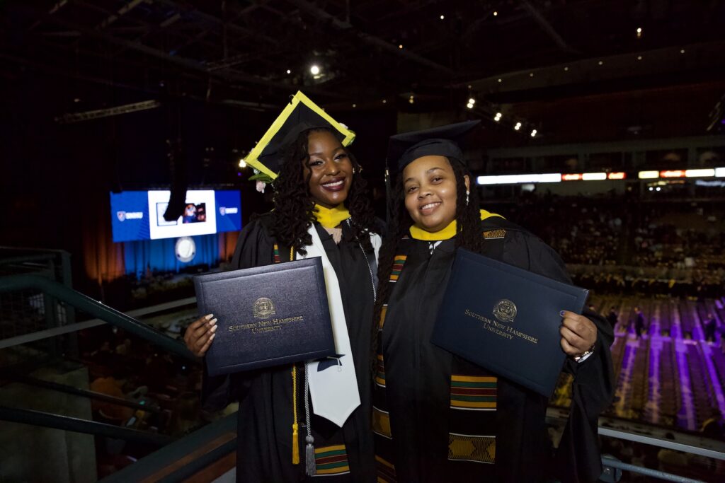 Samiyah and Diana wearing their regalia and posing for photo at SNHU Commencement